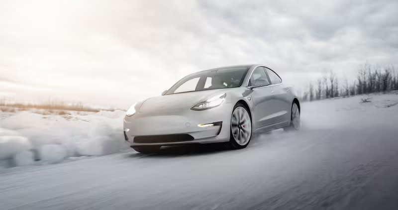 Image of a Tesla driving on a snow-covered road